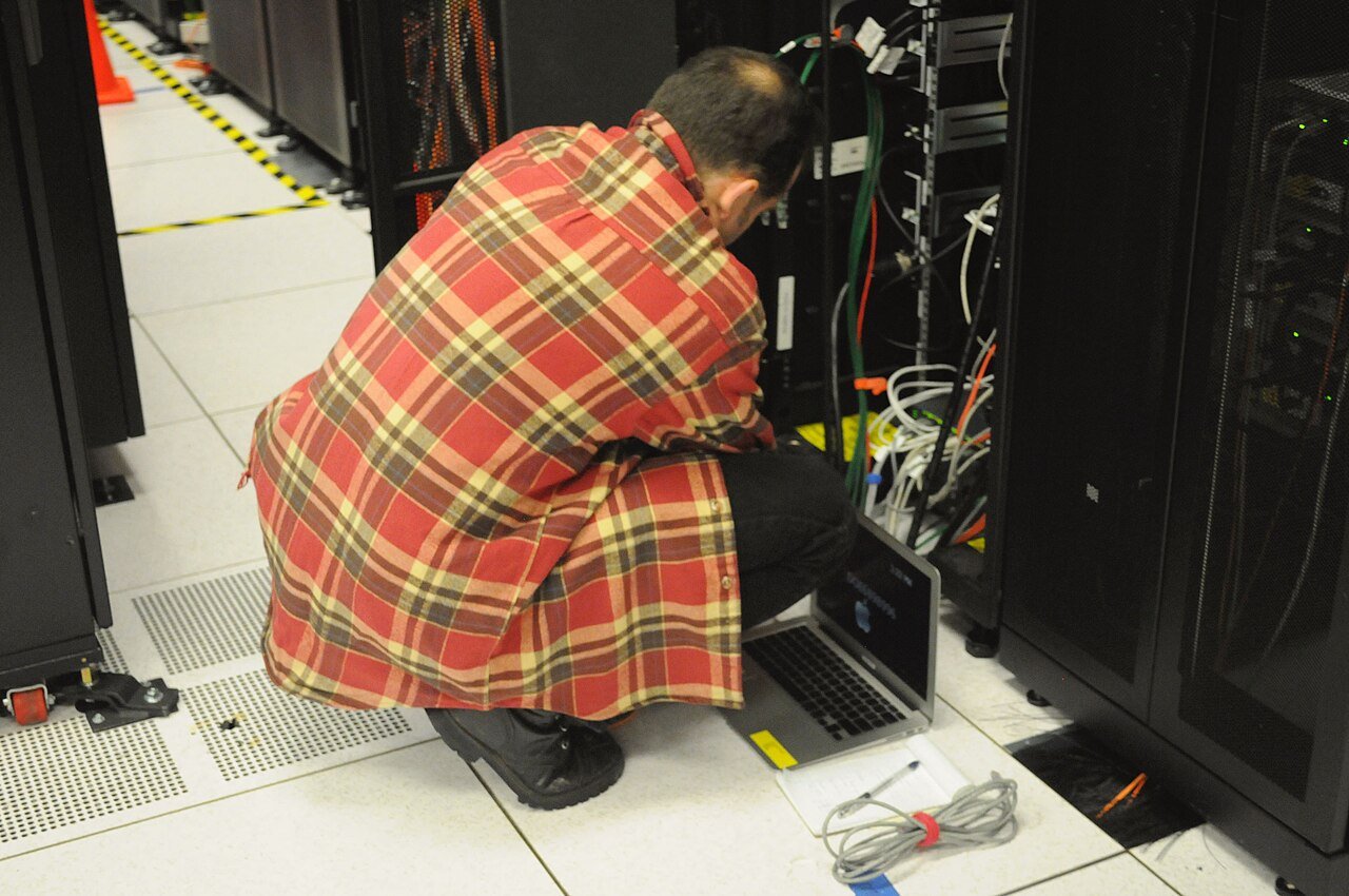 Técnico com notebook trabalhando em um rack de servidores em data center