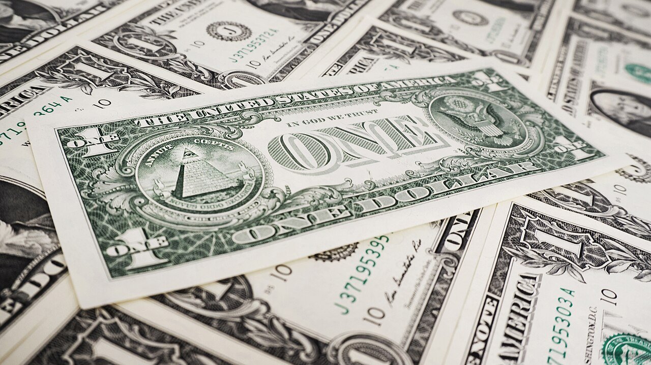 Cédulas de um dólar americano espalhadas sobre uma mesa